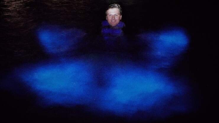 picture of a man swimming in the bio bay with blue bioluminescence around him