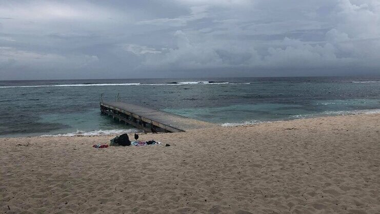 picture of spotts beach with dock in middle and barrier reef in background