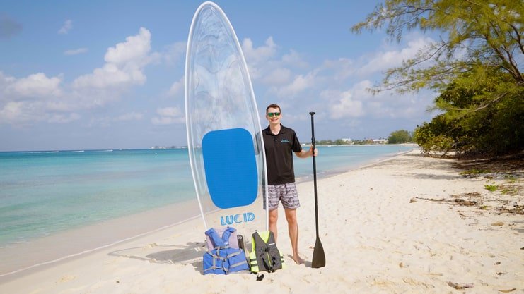 image of a man standing on a beach holding a board next to him